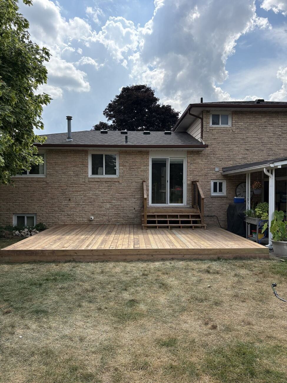 Wide cedar deck behind a brick home in Bolton