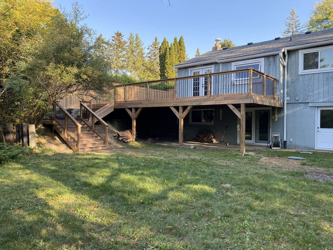 Elevated cedar deck with staircase on a grey home in Palgrave backyard