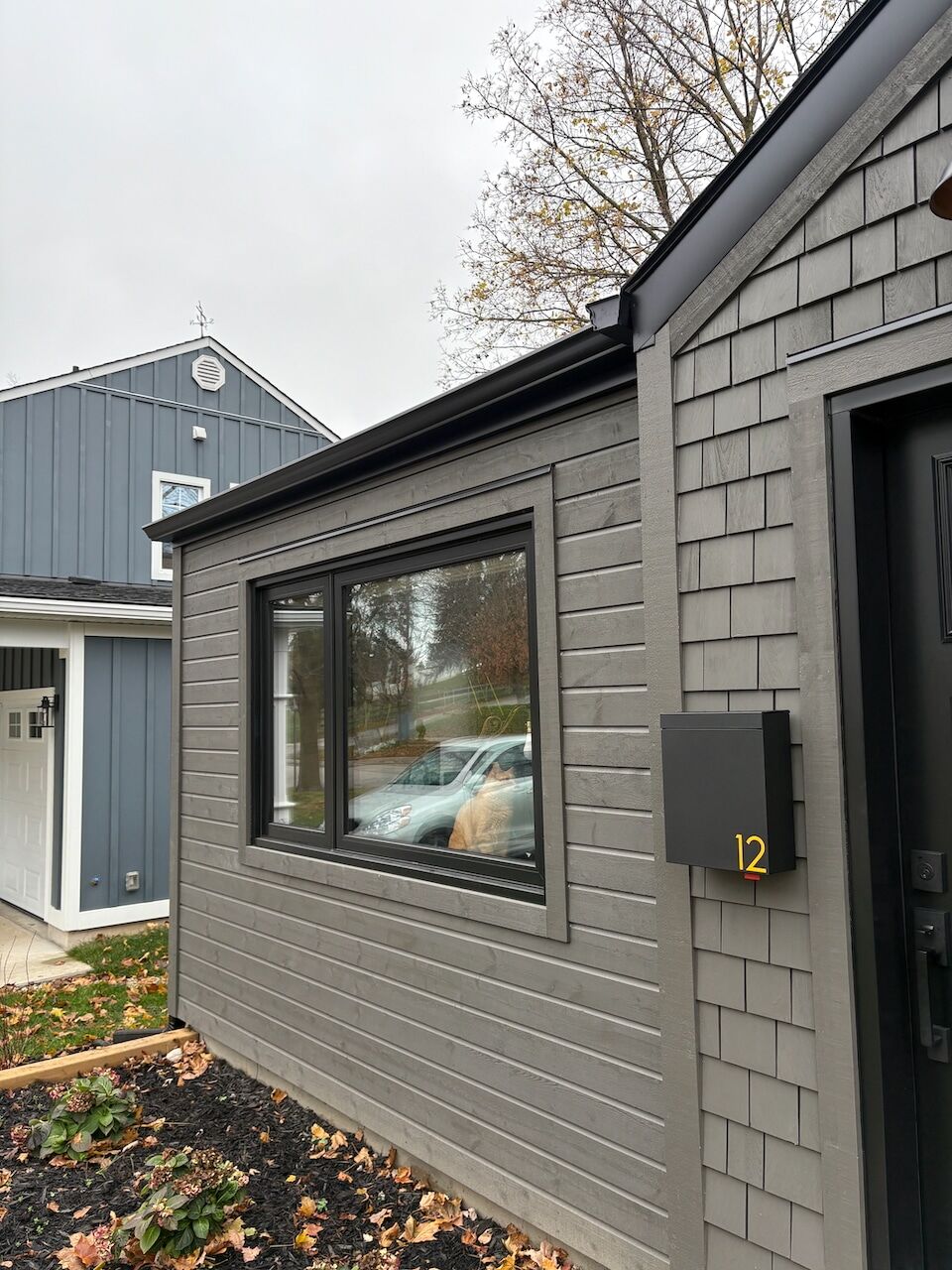 Grey shake siding detail around a black-framed window