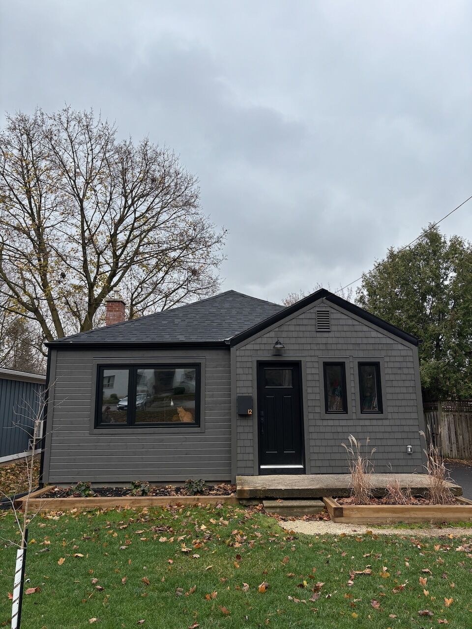 Dark grey re-sided bungalow on a wide lawn, McCarthy project