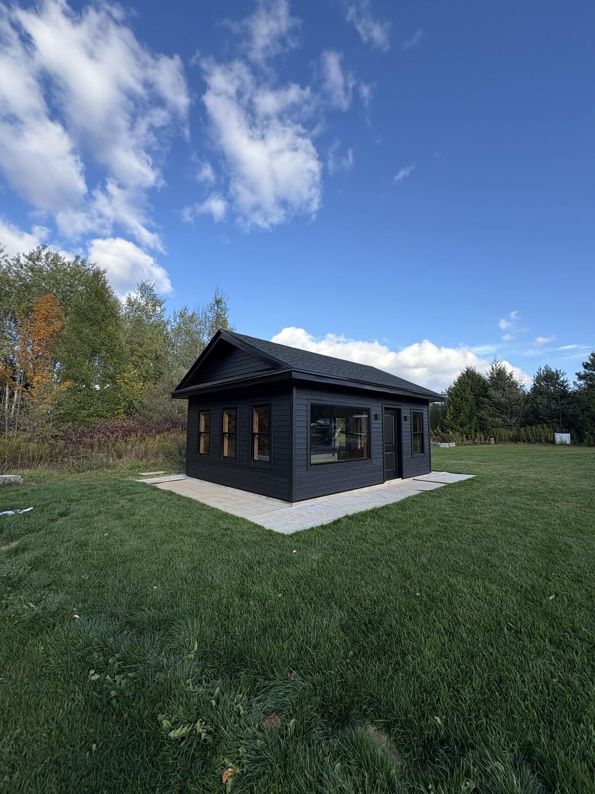 Black-sided backyard studio on a green lawn in Caledon